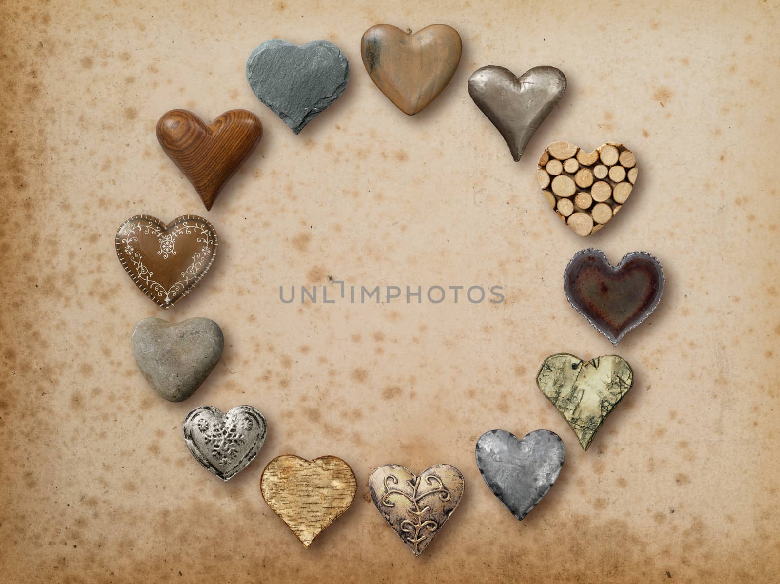 Photo of metal, wood and stone heart-shaped things organized in a circle over vintage paper background.
