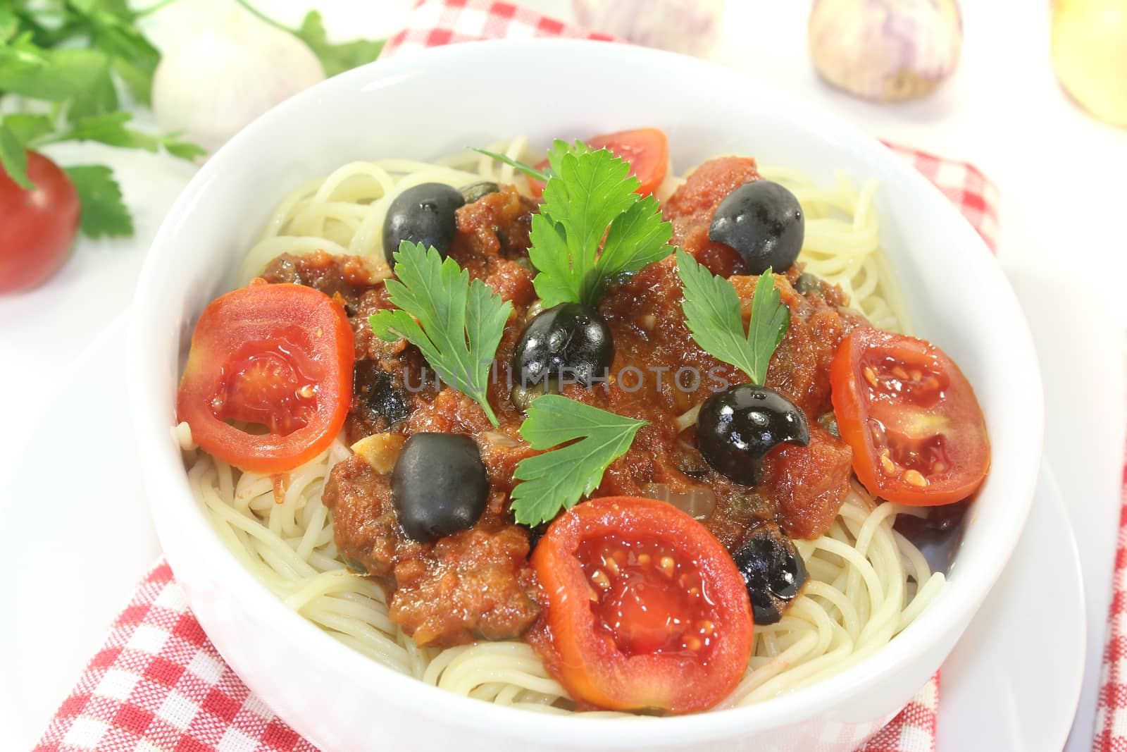 Spaghetti alla puttanesca with olives on light background