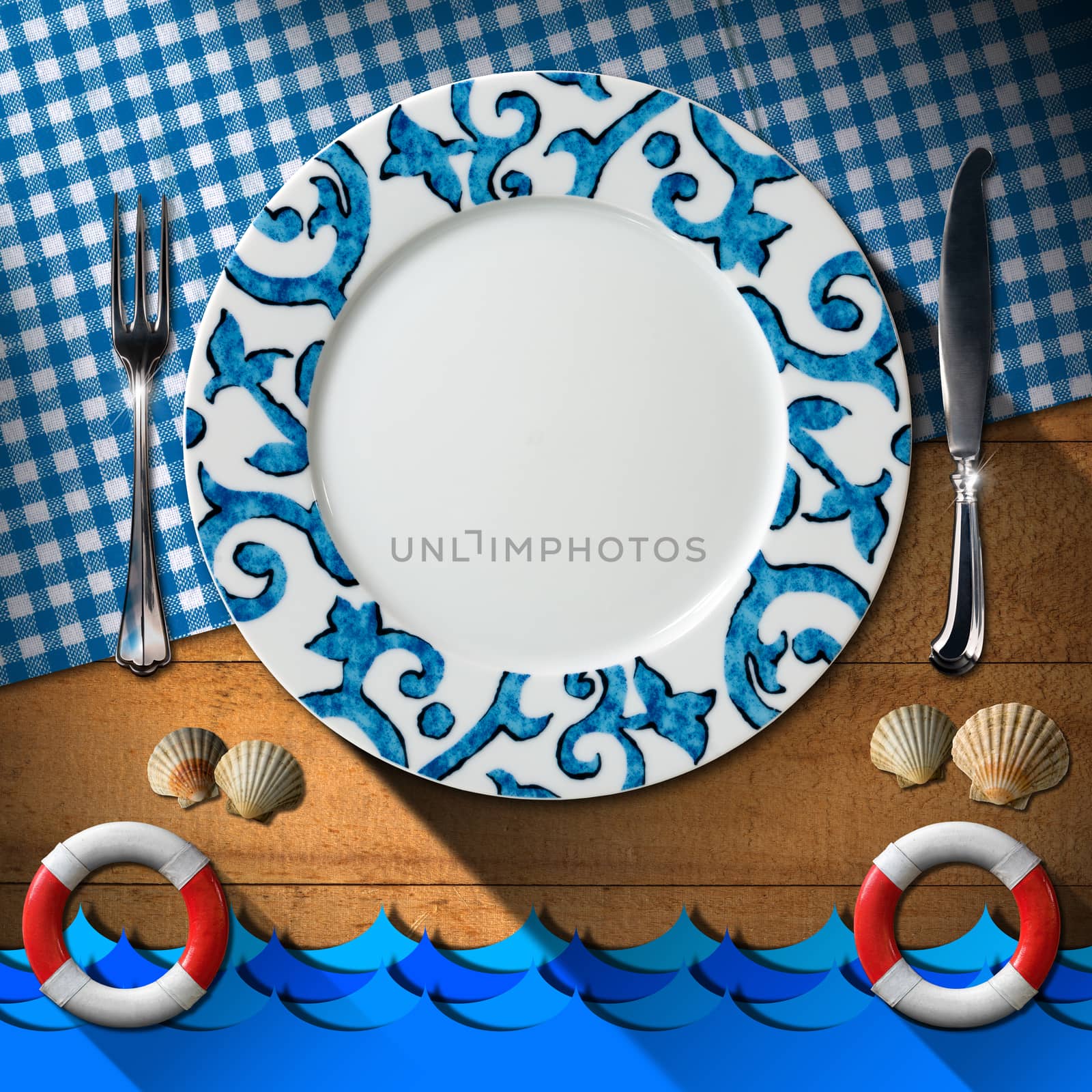 Empty plate with fork and knife, blue and white checkered tablecloth, seashells, blue waves and two lifebuoys. Table set for a seafood menu
