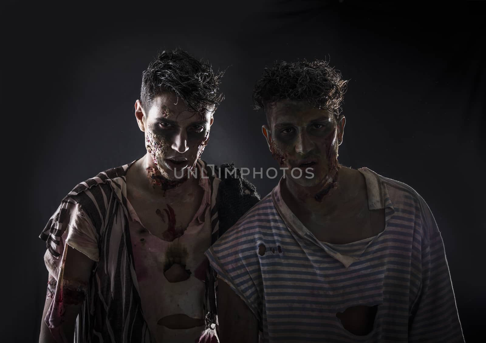 Two male zombies standing on black smoky background, head and shoulder shot. Halloween theme