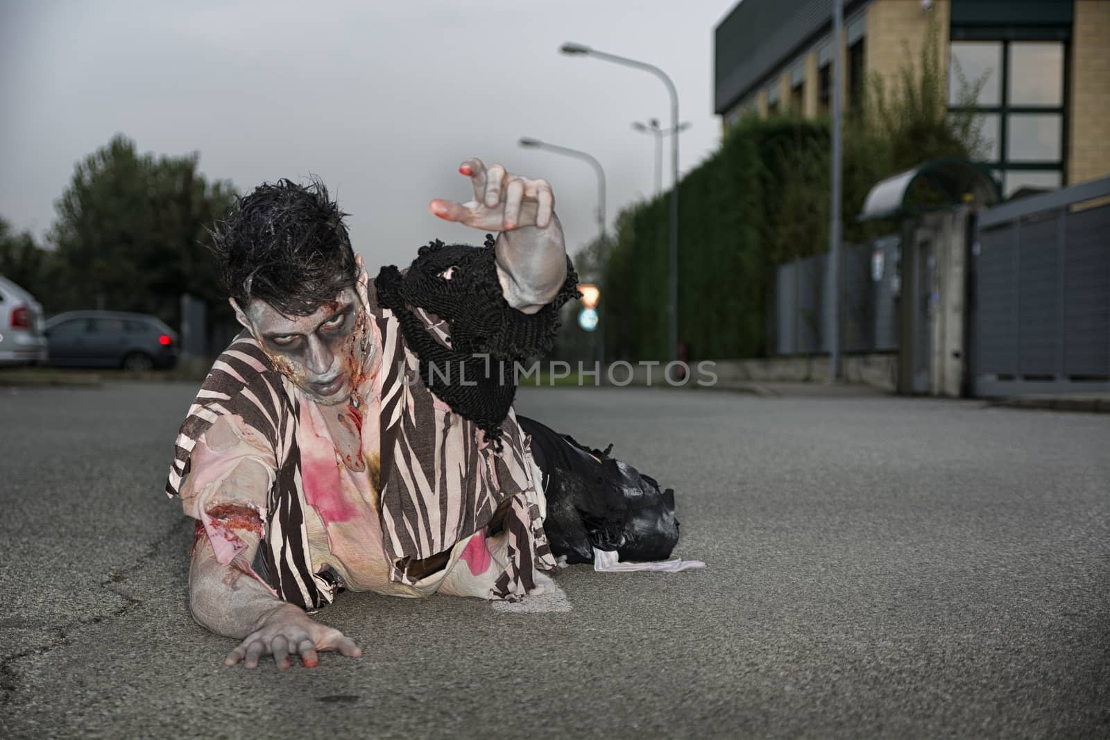 Male zombie crawling on his knees, on empty city street by artofphoto
