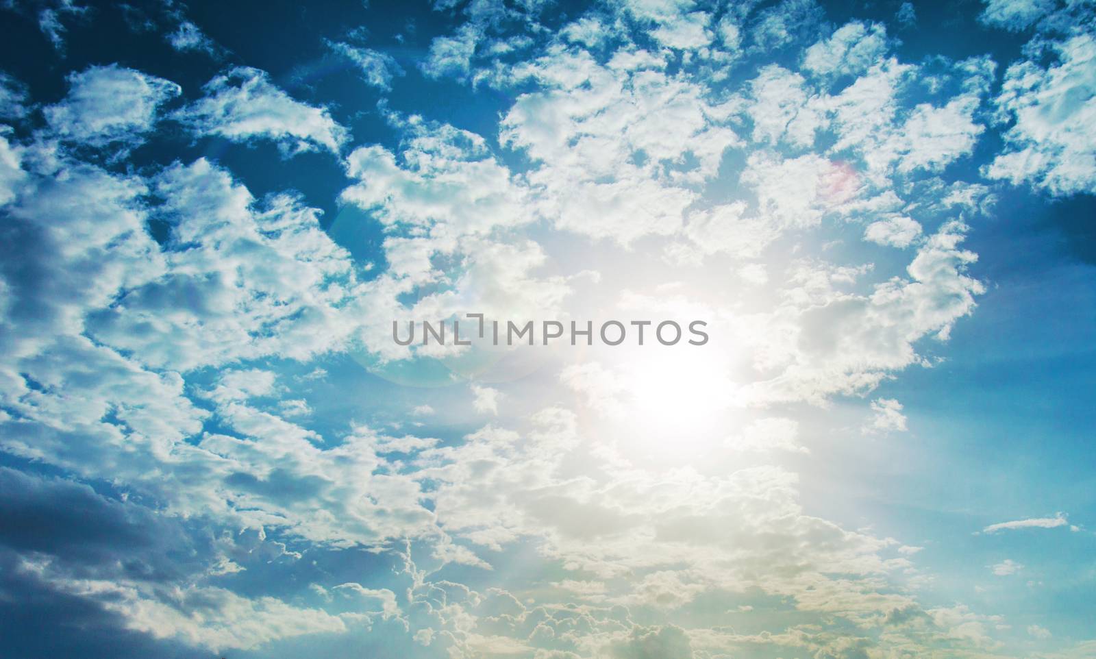 shining sun with lens flare. Blue sky with clouds background by yanukit