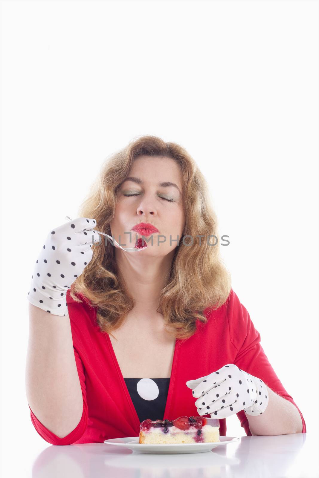 middle-aged woman in red with gloves eating cake