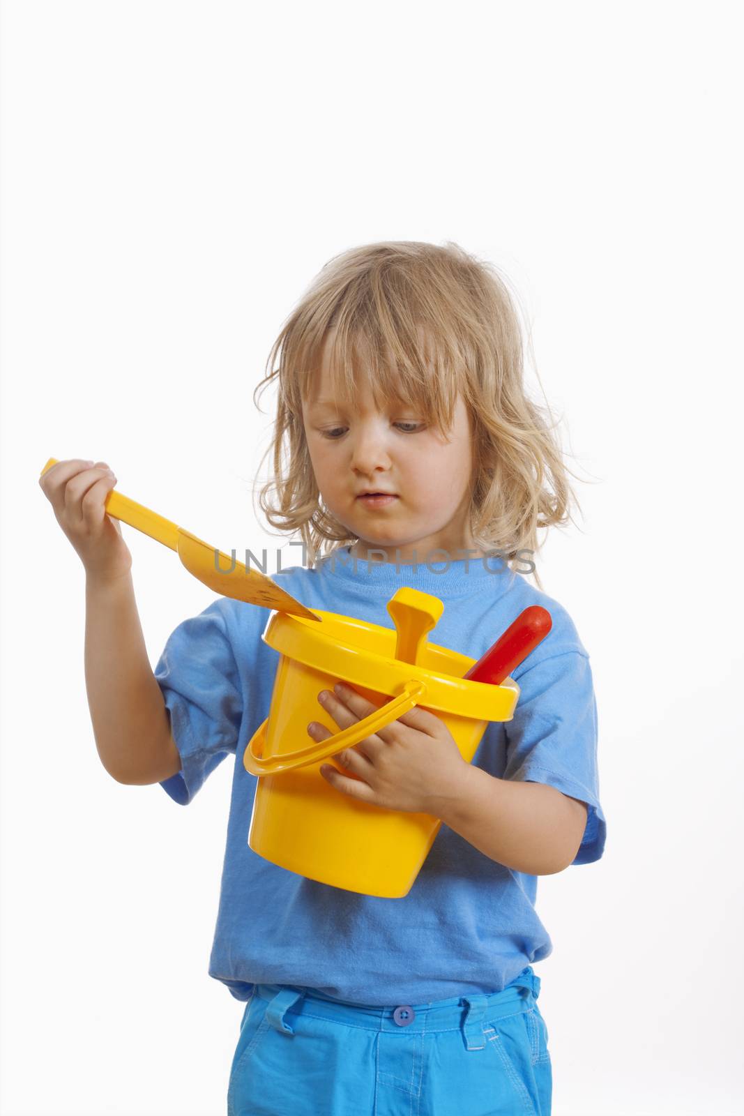 boy with long blond hair carrying colorful plastic beach toys - isolated on white