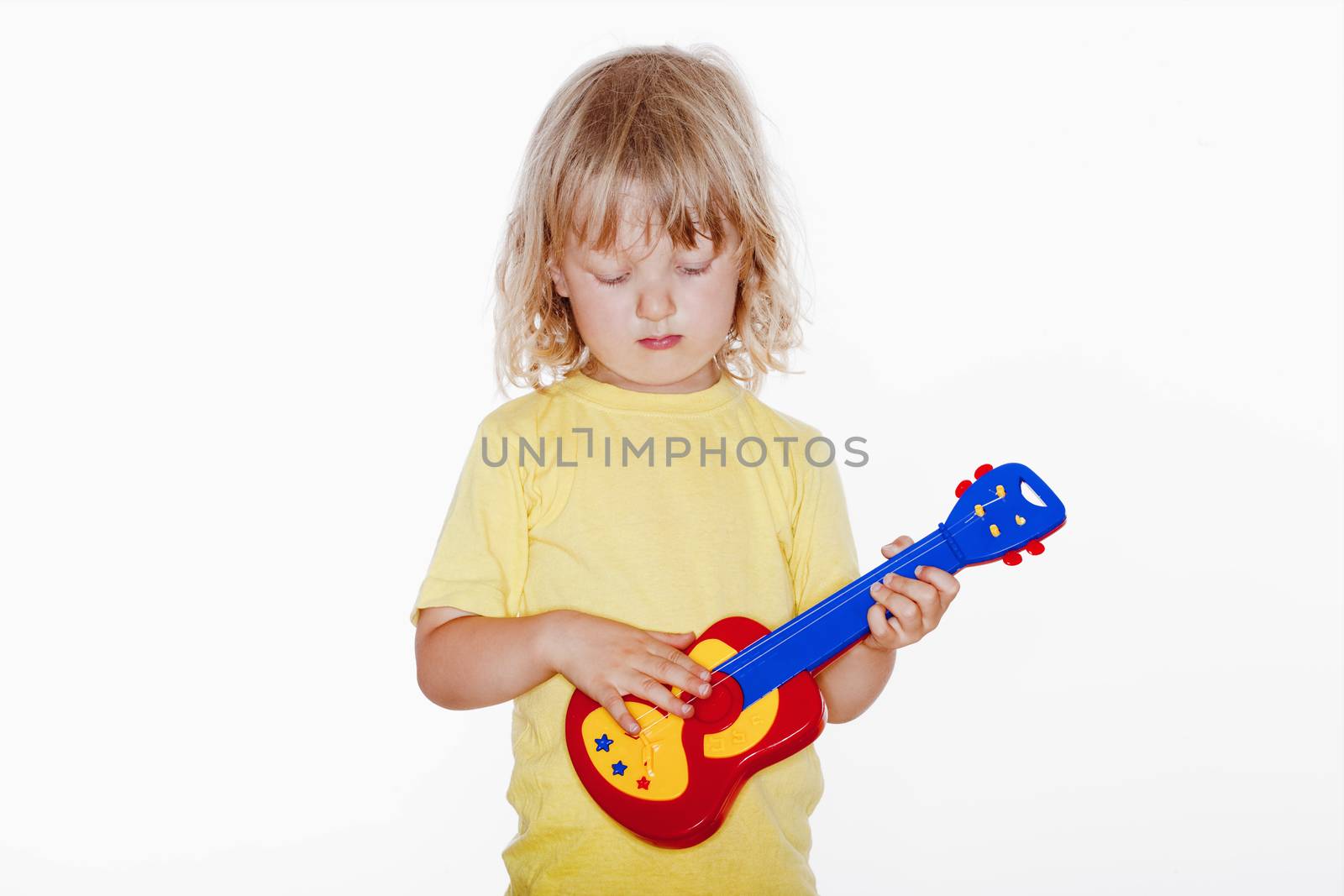 boy with long blond hair playing with toy guitar - isolated on white