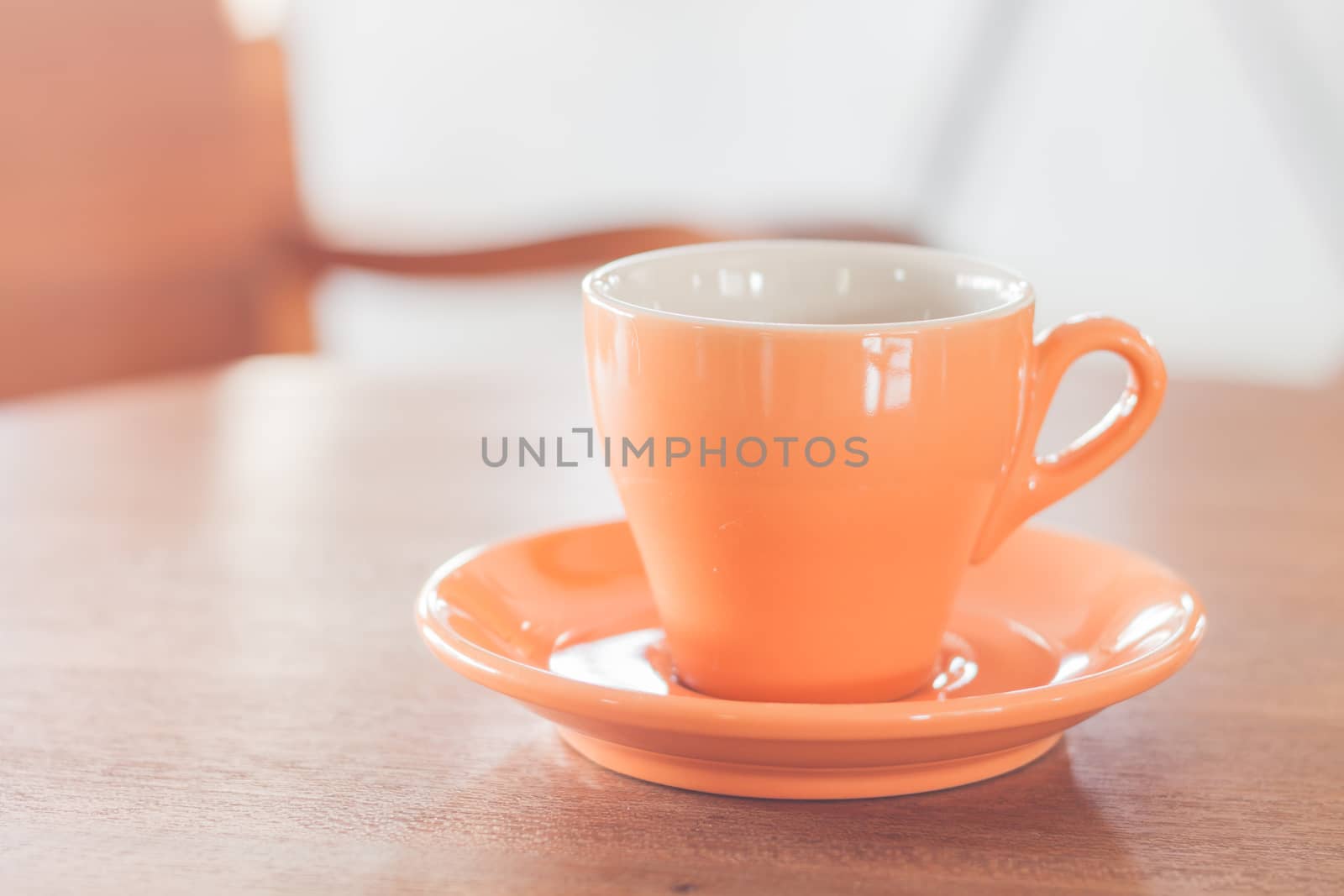 Orange coffee cup on wooden table, stock photo