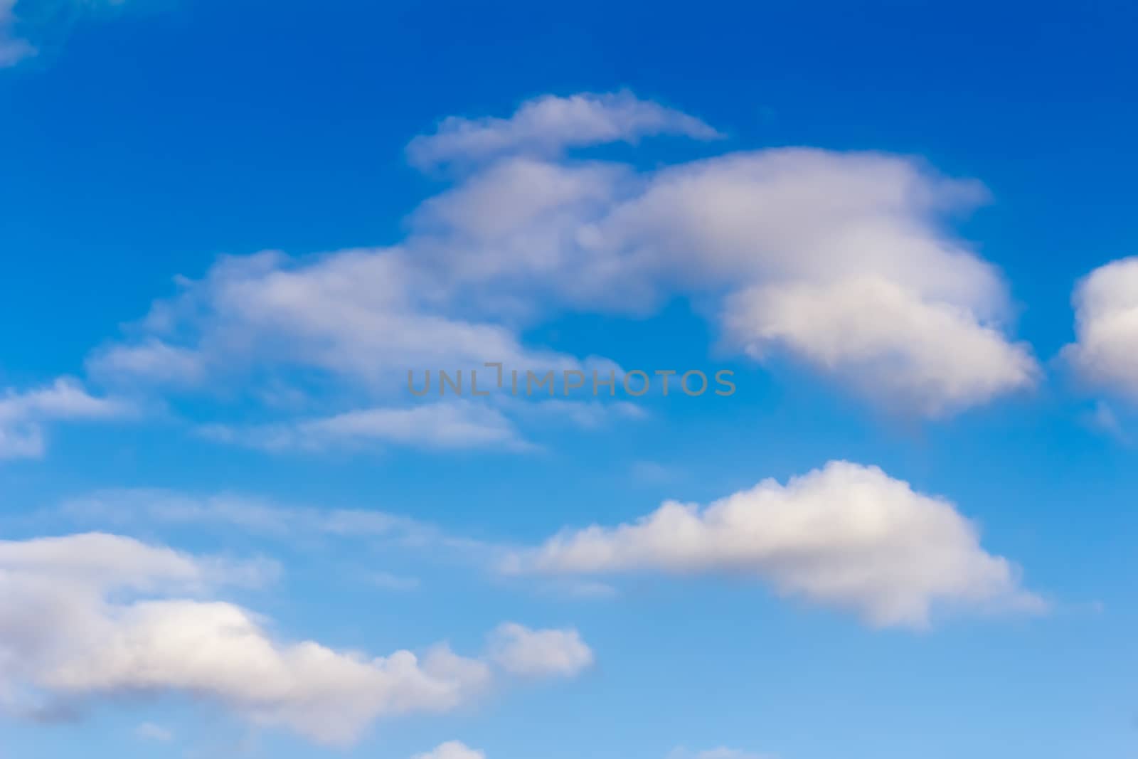 White fluffy clouds float on the blue sky in a clear sunny day.