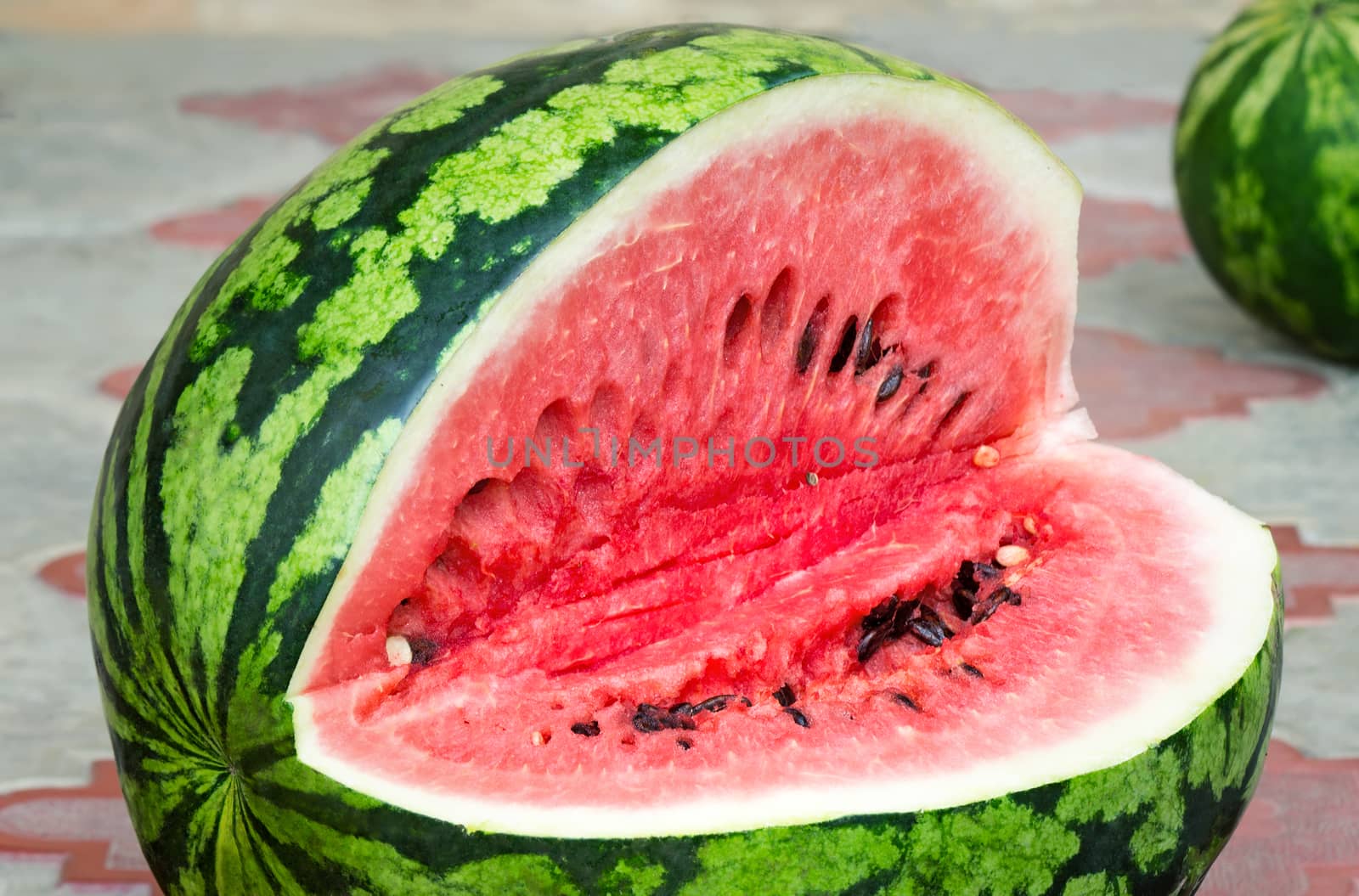 On the surface of the table on a plate of sliced watermelon with dark seeds inside. Presents closeup.