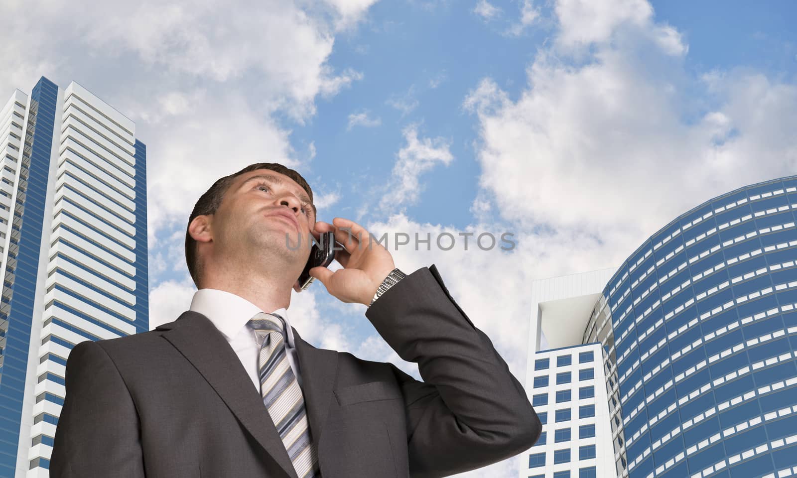 Businessman talking on the phone. Skyscrapers and clouds in background