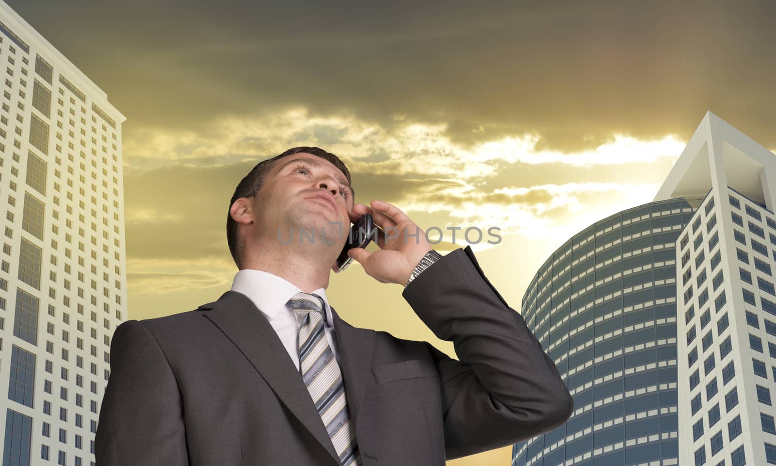 Businessman talking on the phone. Skyscrapers and clouds in background