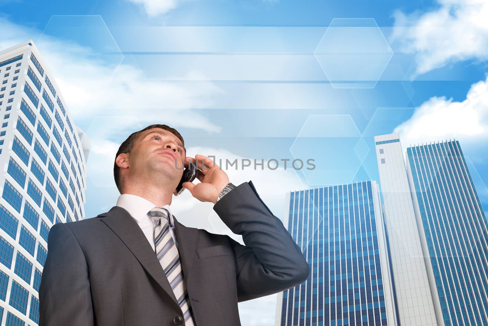 Businessman talking on the phone. Skyscrapers and sky with clouds in background