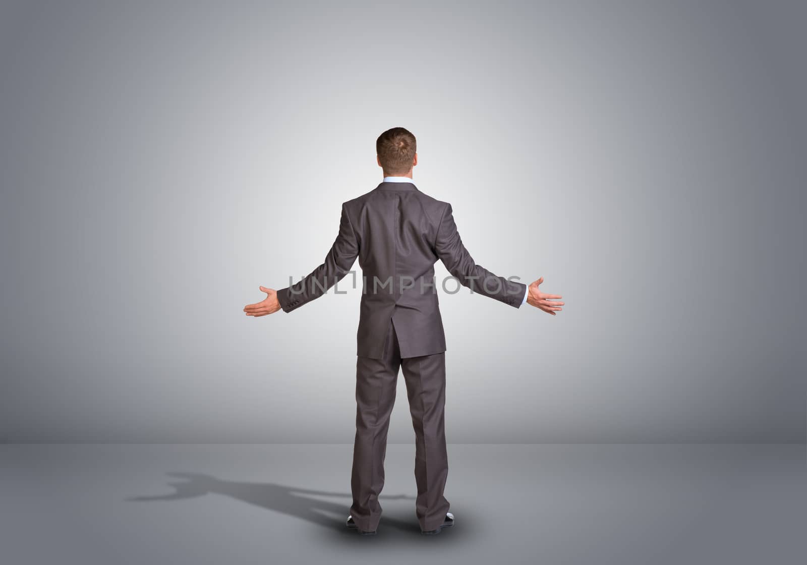 Businessman standing in an empty gray room. Rear view by cherezoff