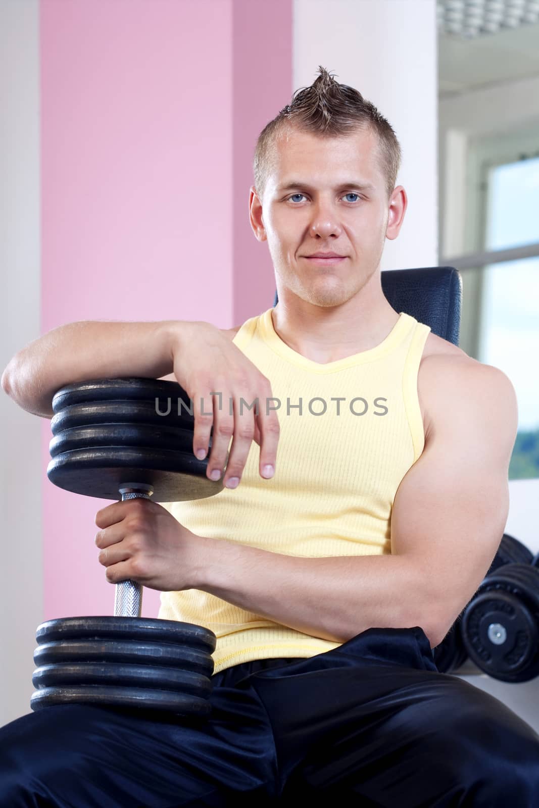 portrait of a young man holding dumbbells in modern gym