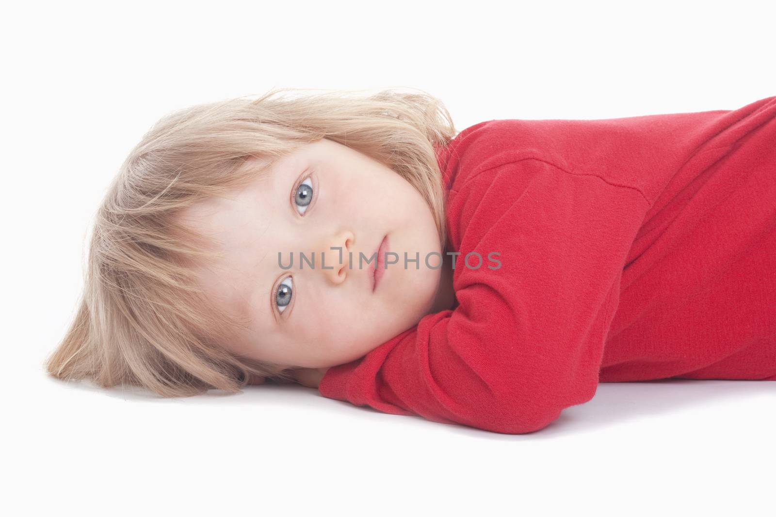 boy with long blond hair lying down, looking at camera - isolated on white