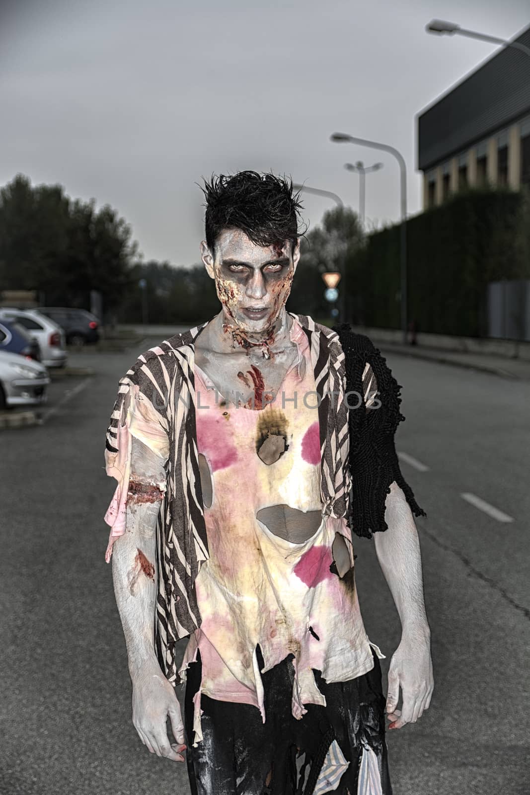 One male zombie standing in empty city street on Halloween by artofphoto