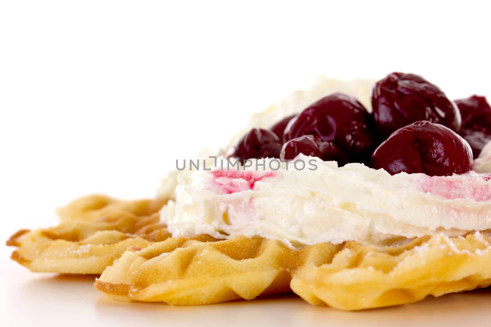 Close-up of waffle with whipped cream and cherries by gwolters