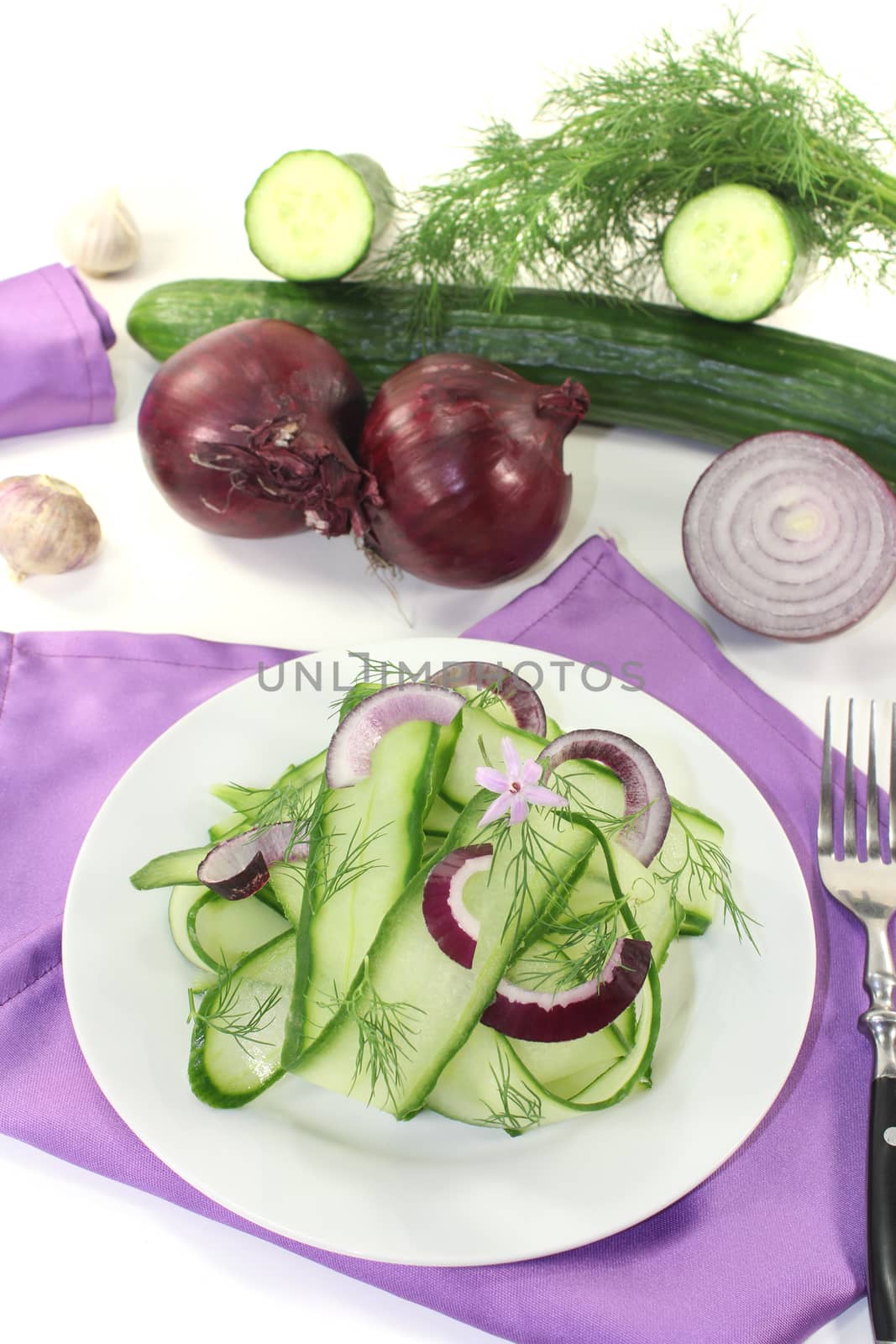 Cucumber salad with onions, garlic flower and dill on light background