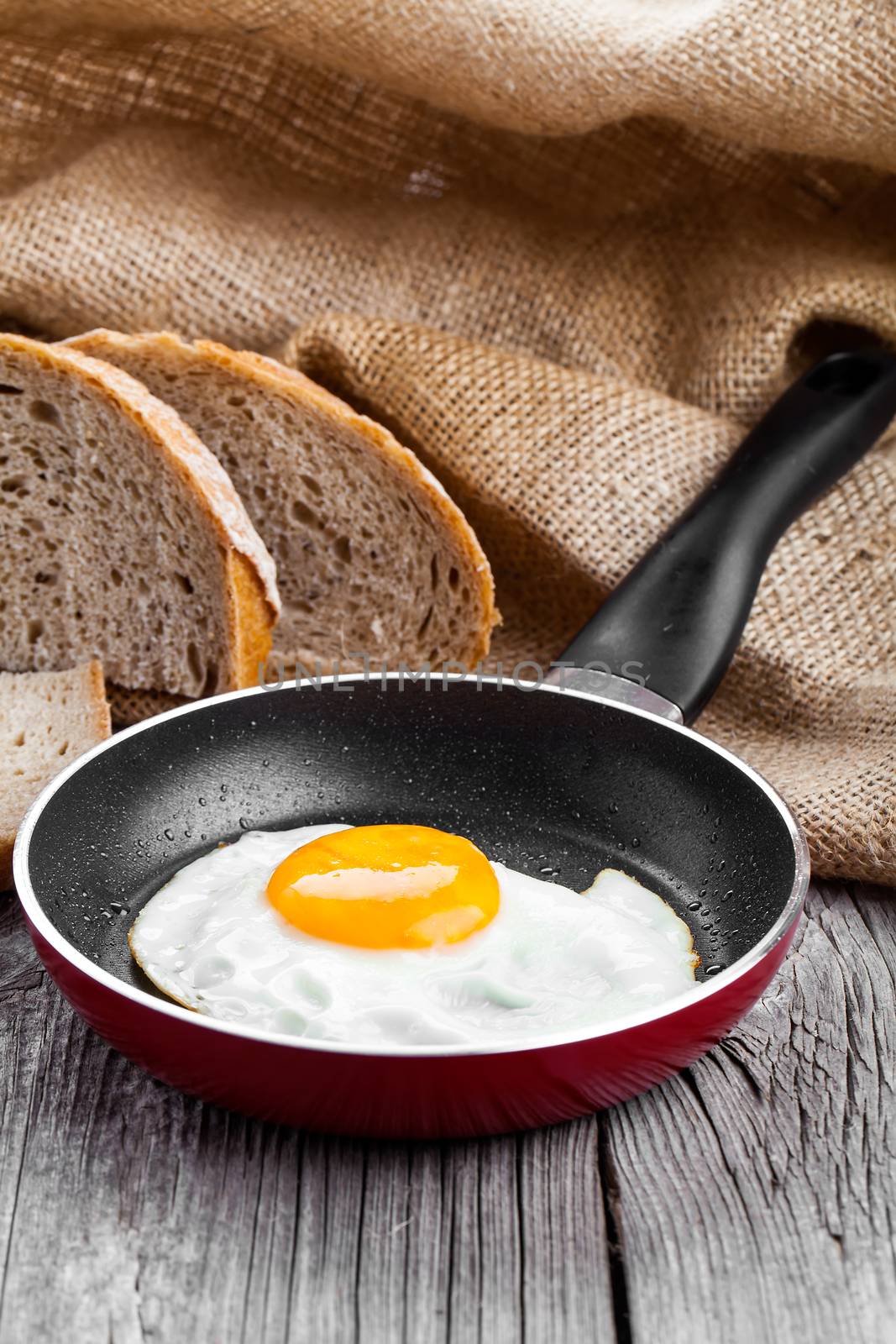 Fried egg in a frying pan, on an old wooden table by motorolka