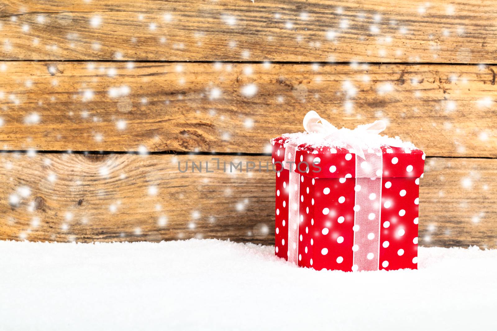 red gift for christmas on a wooden background with snow