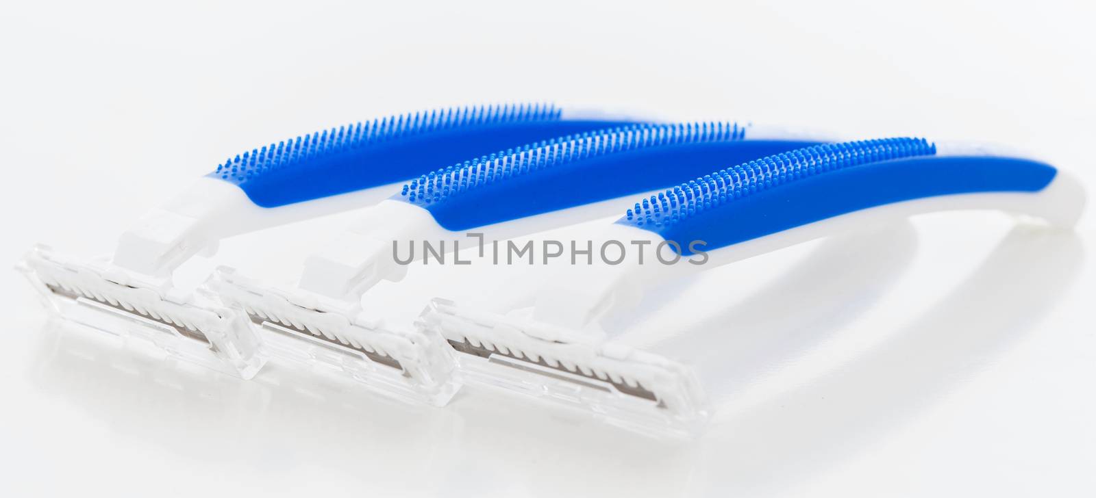 Picture of a few white and blue razors for men over a white background