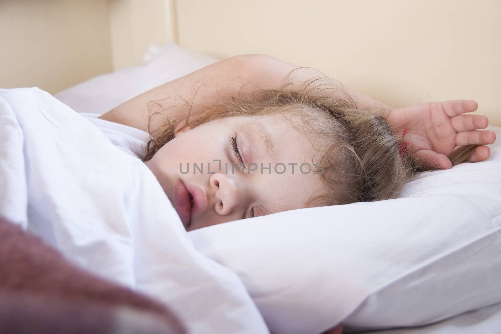 Two-year-old girl sleeping in the train. Close-up. White linens.