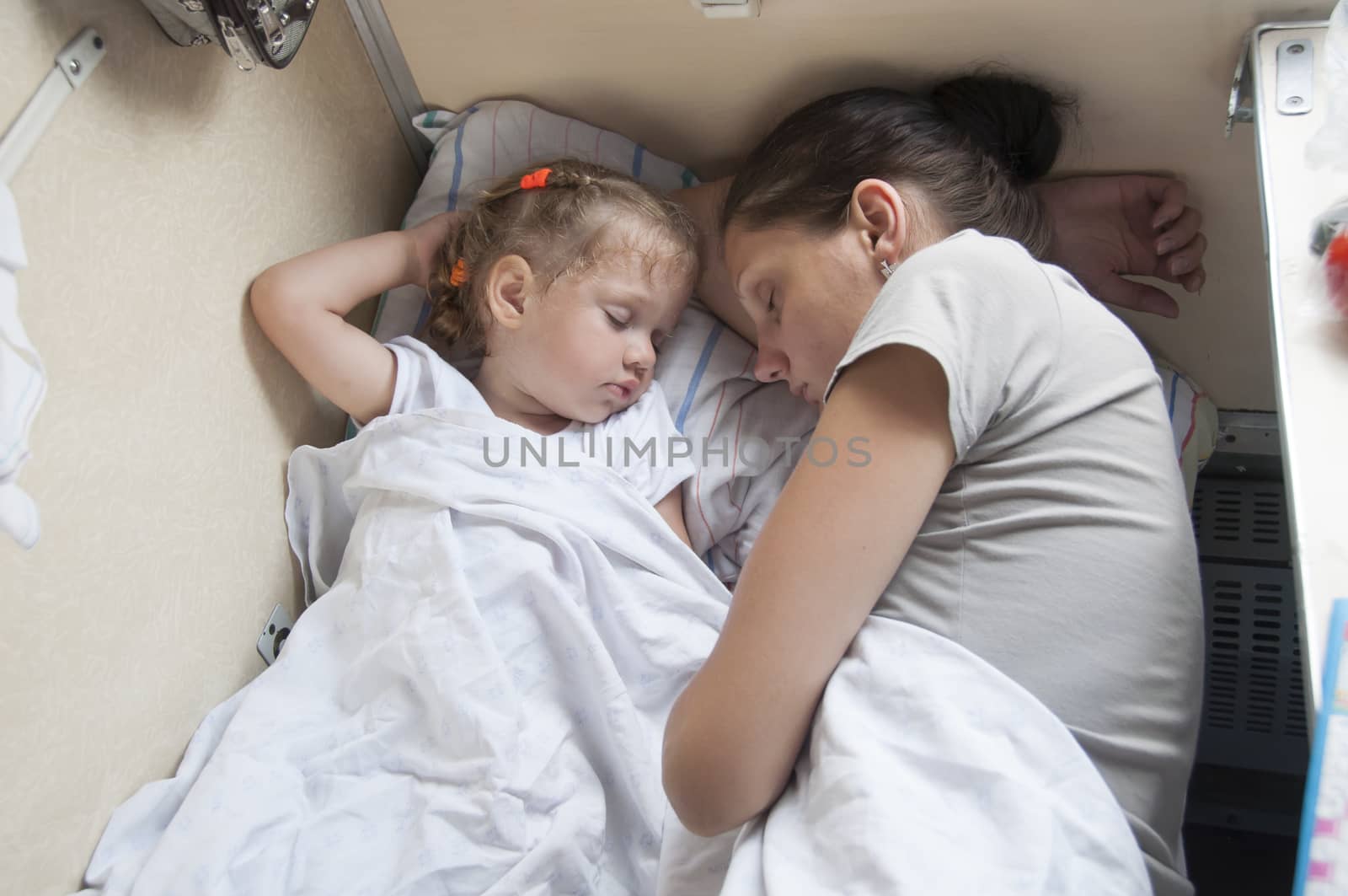 Mother and two year old daughter sleeping on a cot in a parlor car trains.
