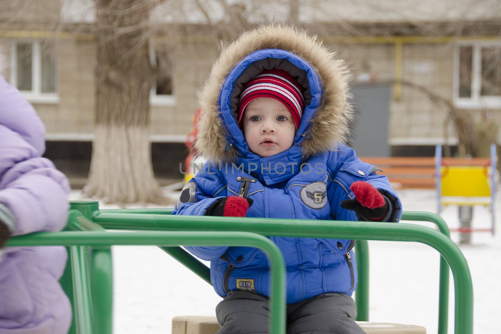 A little girl riding a little merry-go-round on the Playground. The girl is afraid of.