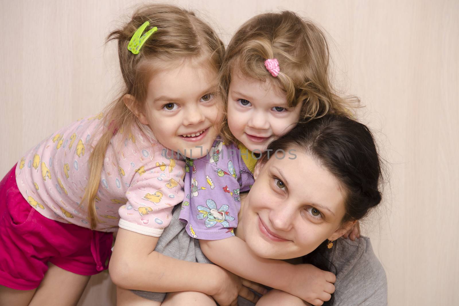 family of the house, my mother, two-year and four-year-old daughter. The younger daughter hung on the mother's neck, the eldest daughter lay down on the shoulder of the younger. Smile and look in the frame.