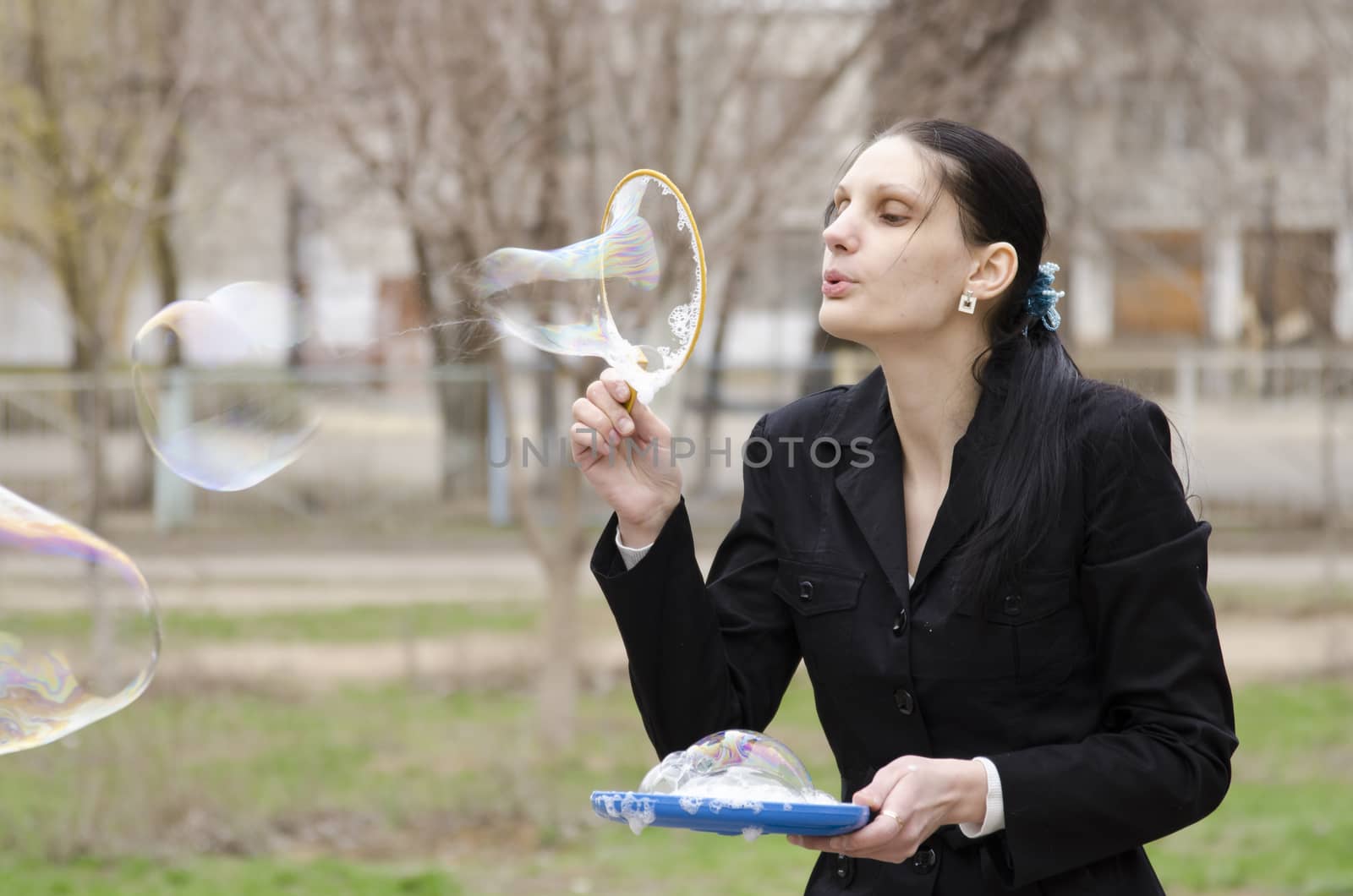 A girl inflates a big bubble. The bubble bursts. Street, early spring