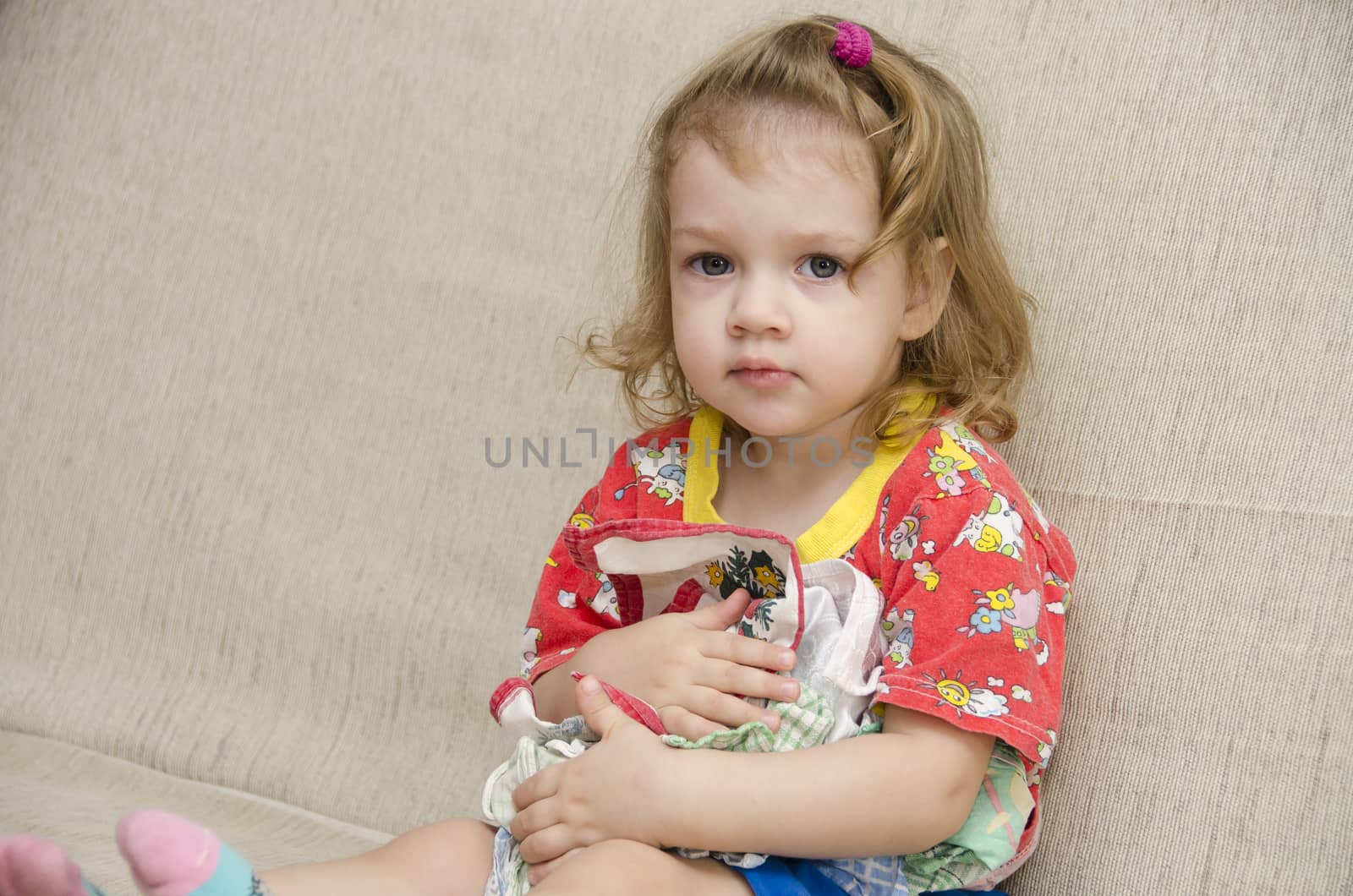  A little girl sits on the couch. To itself the girl pressed a few handkerchiefs not wanting to give them to anyone