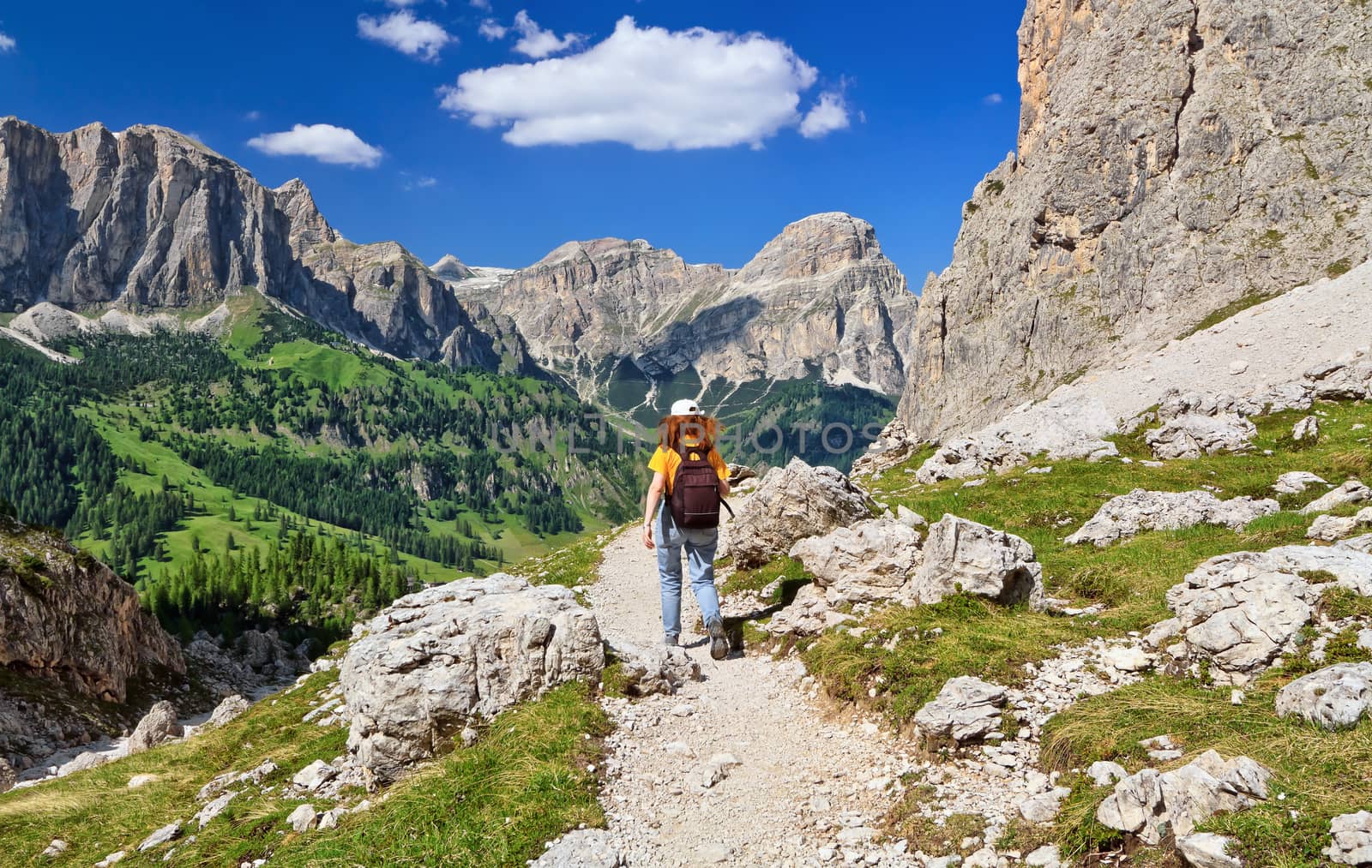 hiker on footpath  in Sella mountain, on background Colfosco and Badia Valley, south Tyrol, Italy