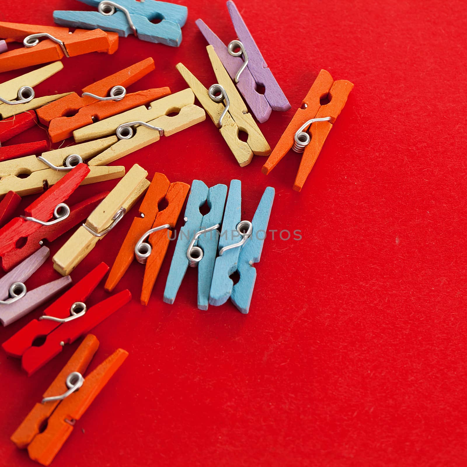 Closeup image of little colorful office clothespins on a red background