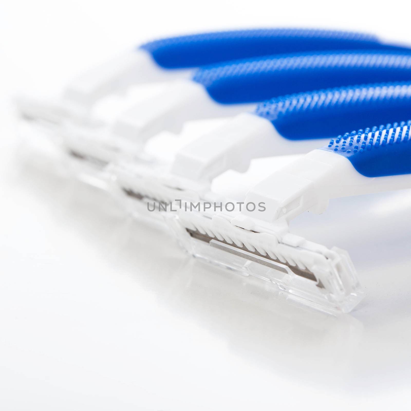 Picture of a few white and blue razors for men over a white background