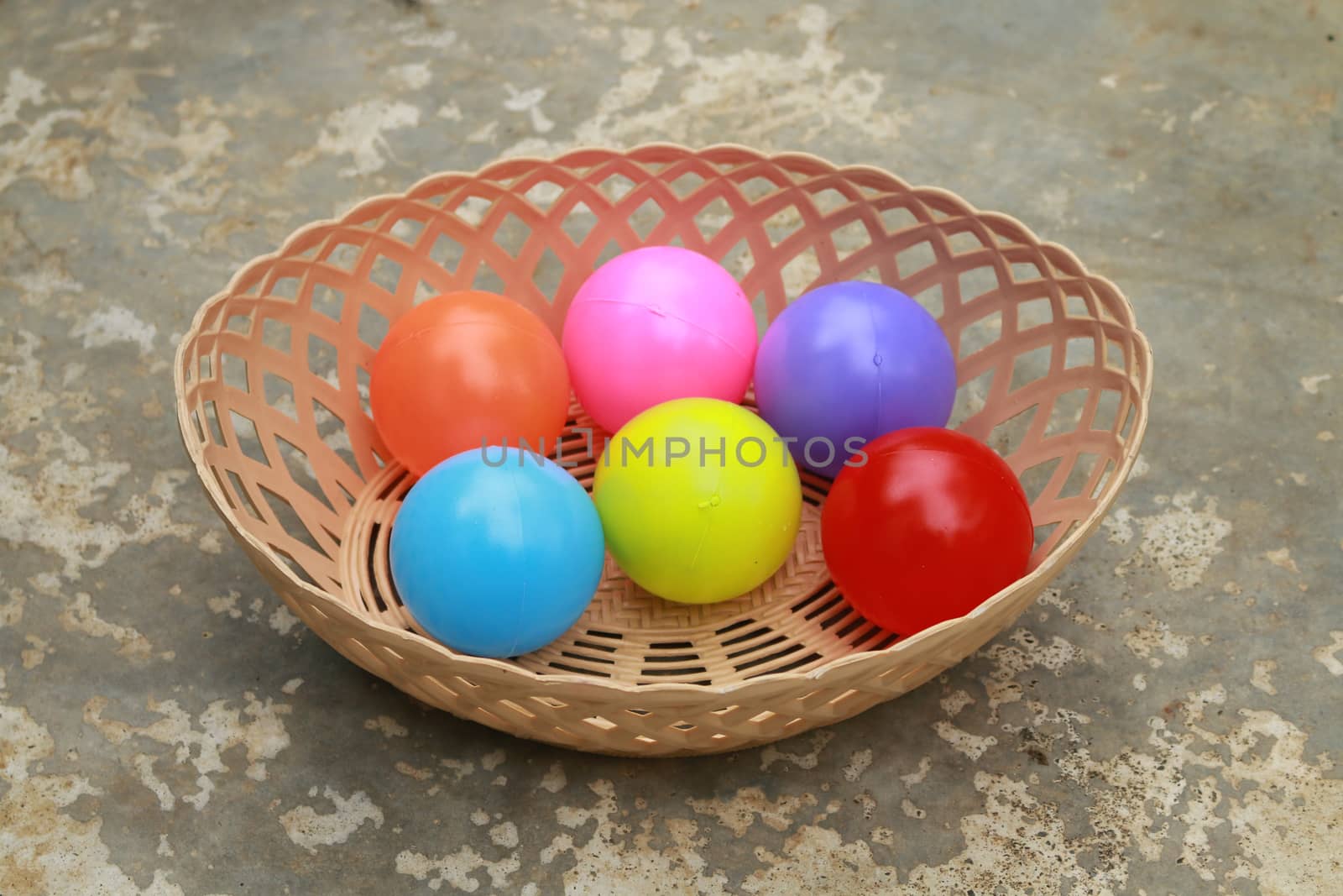 There are many colour balls in the basket.All made from plastic.