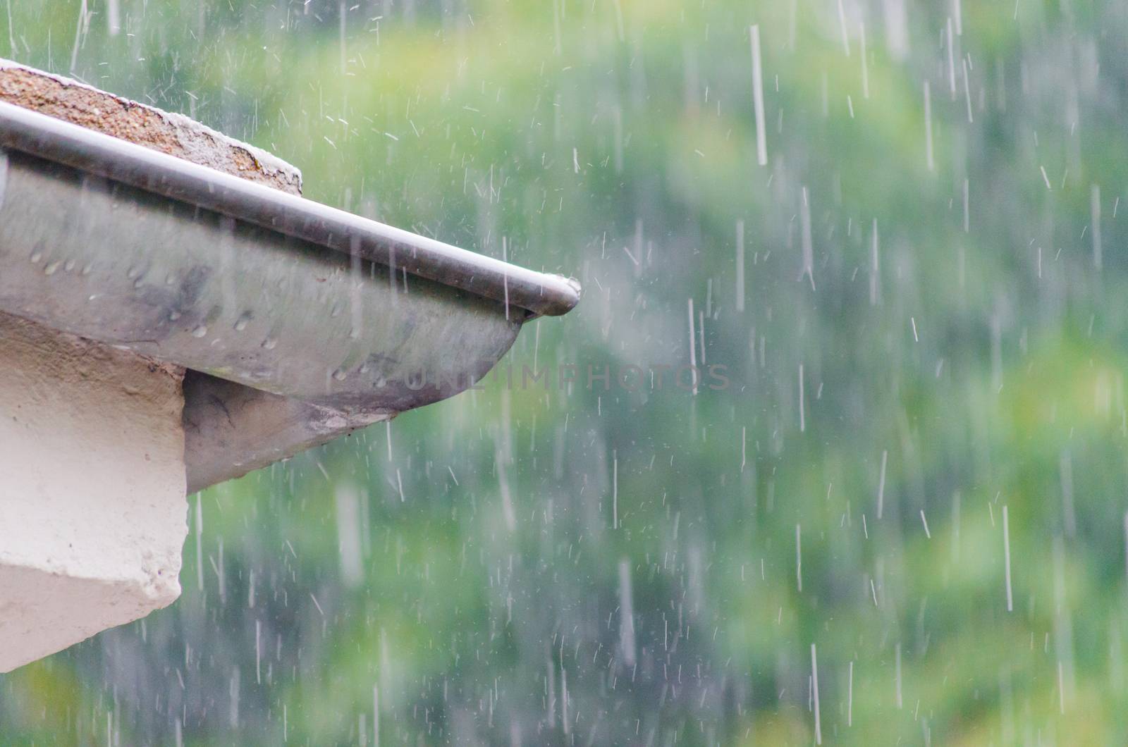 Overlooking a roof gutter with raindrops on a balcony during heavy rainfall.