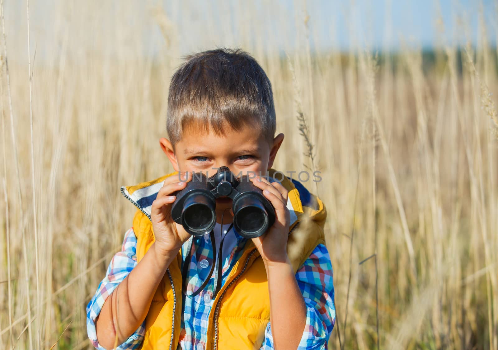 Young boy child playing pretend explorer adventure safari game outdoors with binoculars and bush hat