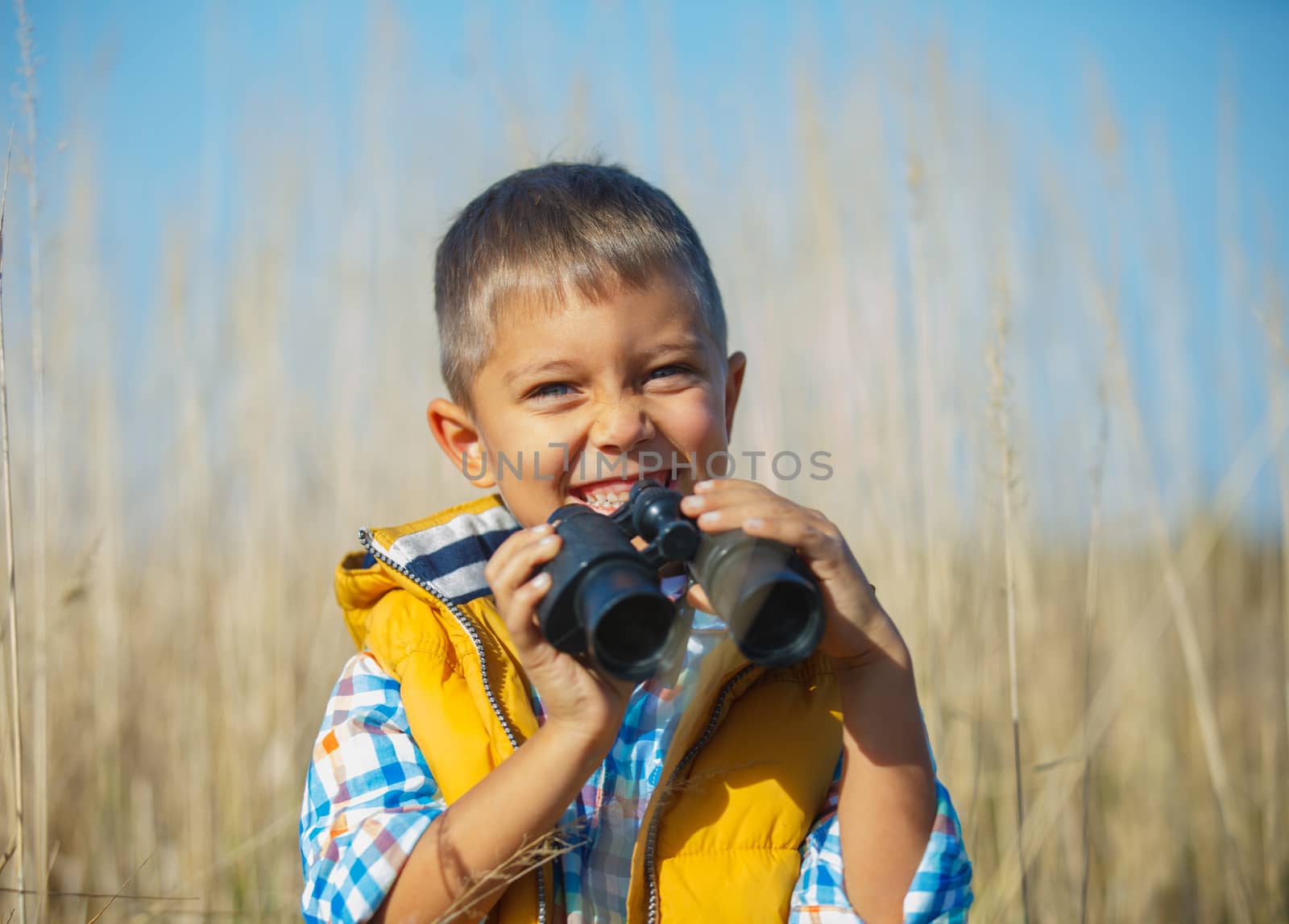 Young boy child playing pretend explorer adventure safari game outdoors with binoculars and bush hat