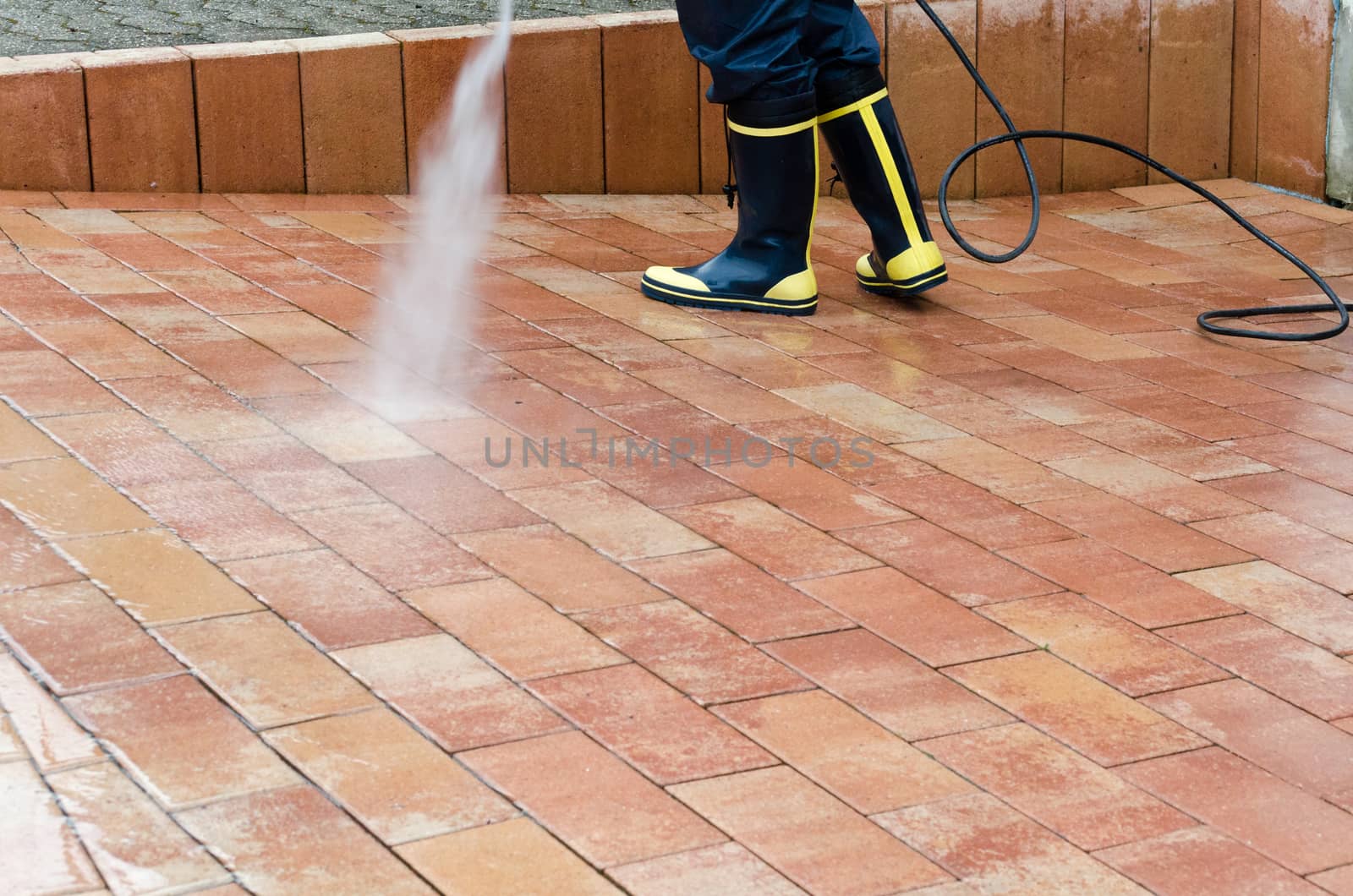 Workers cleaning with high pressure cleaner the entrance of a car garage
