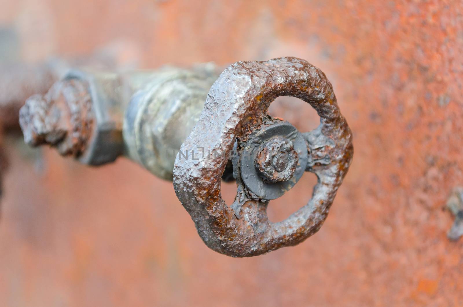Old rusted Abperrventil slider with threaded front of a rusty background

