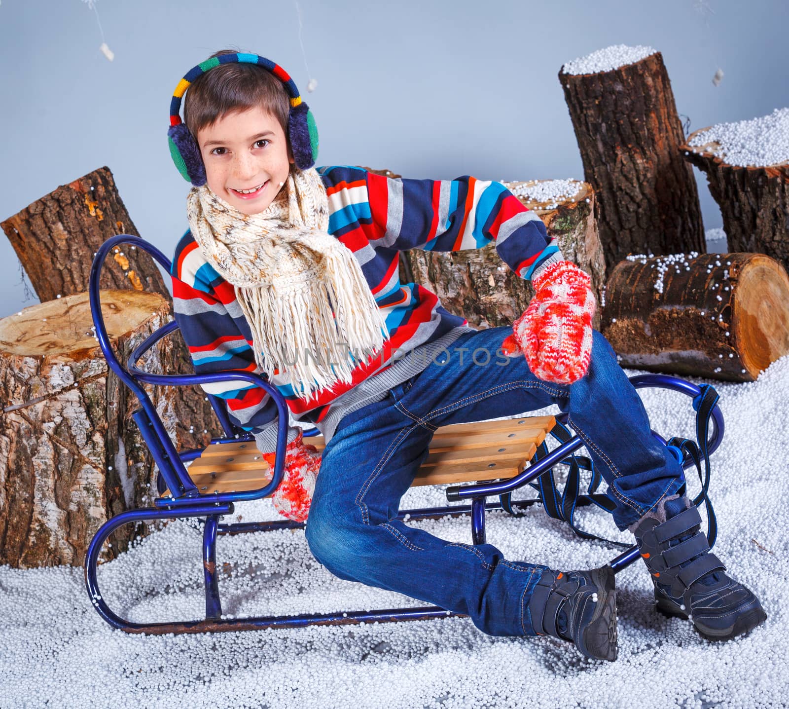 Winter Fashion. Portrait of adorable happy boy in winter hat, gloves and sweater in studio.