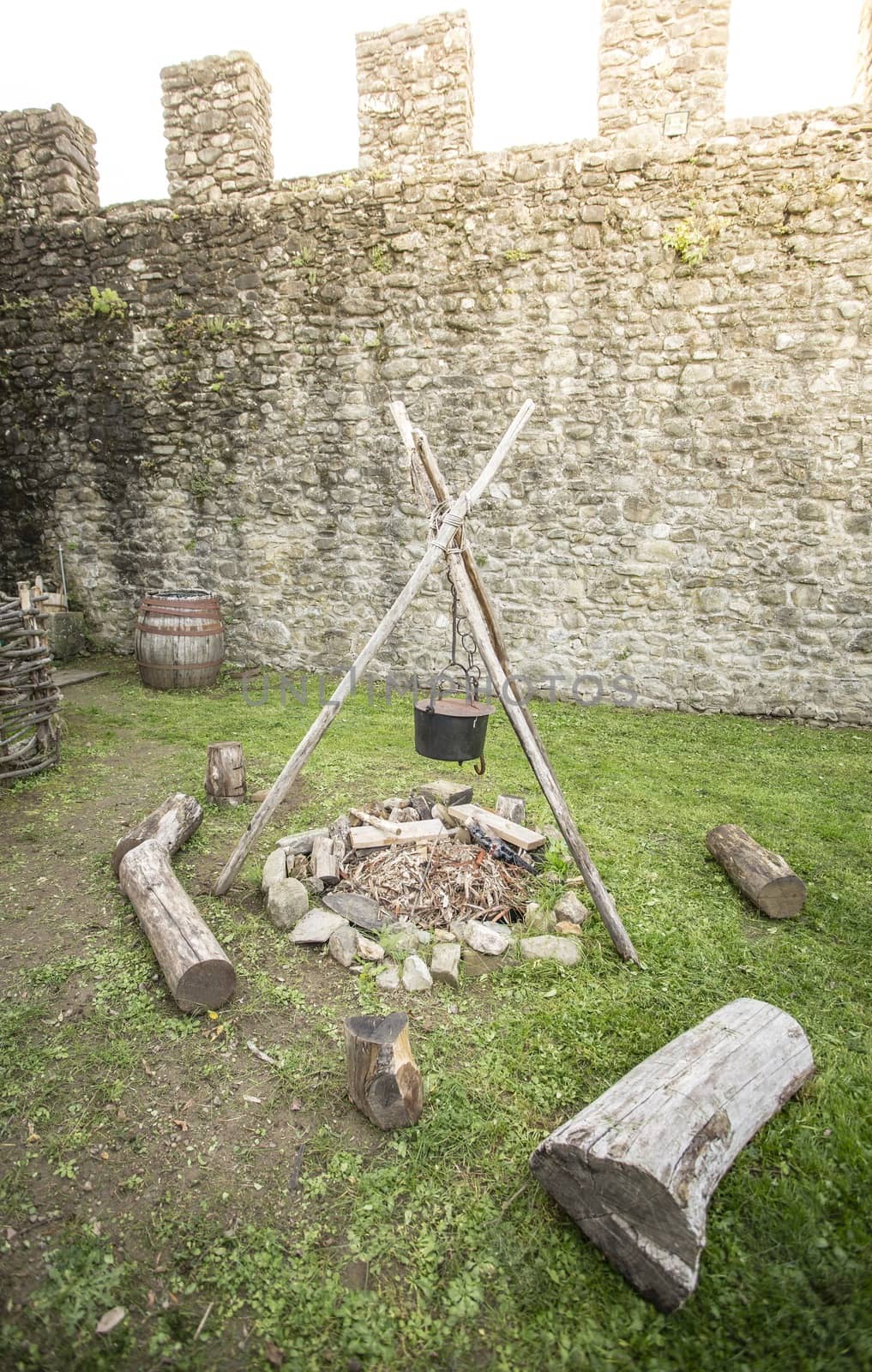 A medieval campfire with stone walls in the background