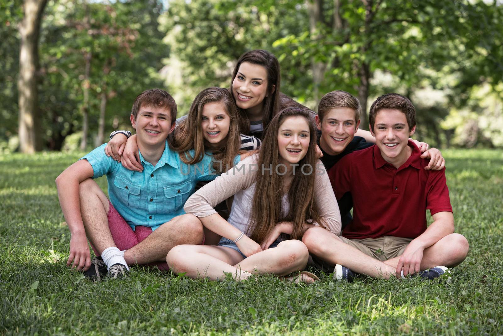 Teen boys and girls sitting on grass outdoors