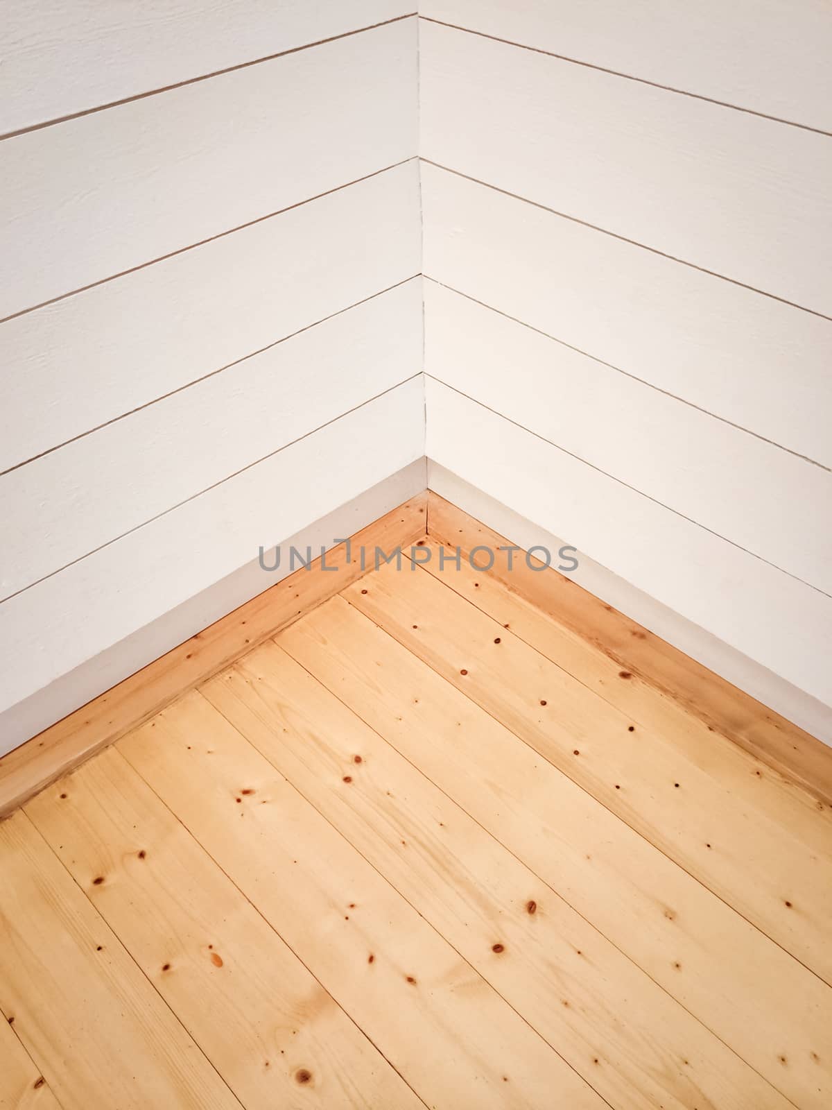 Empty room corner with wooden floor and white painted wall.