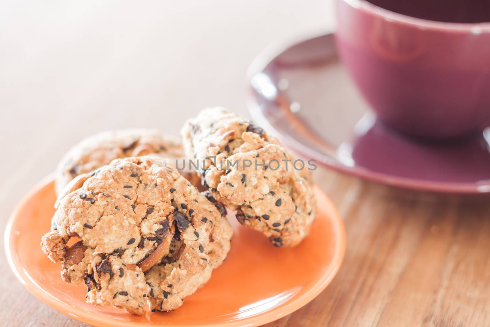 Closeup cereal cookies on orange plate and coffee cup by punsayaporn