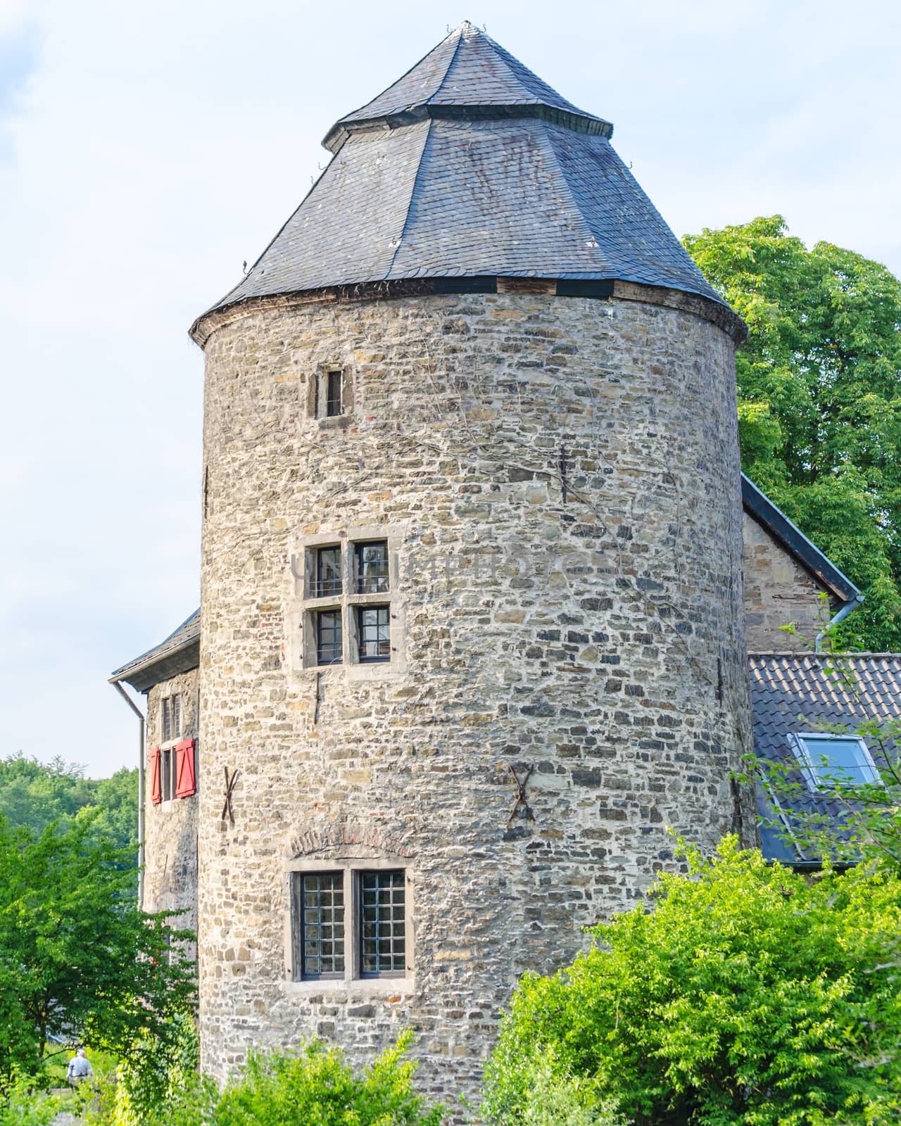 Age castle tower against blue sky and other historic parts of the building.