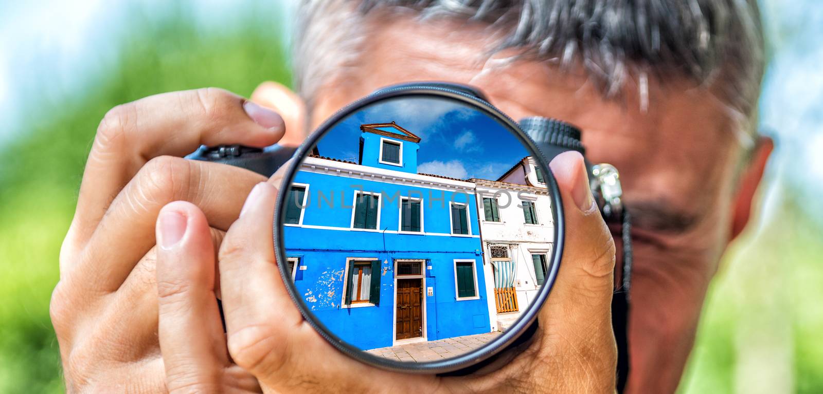 Photographer taking photo with DSLR camera at Burano buildings. Shallow DOF