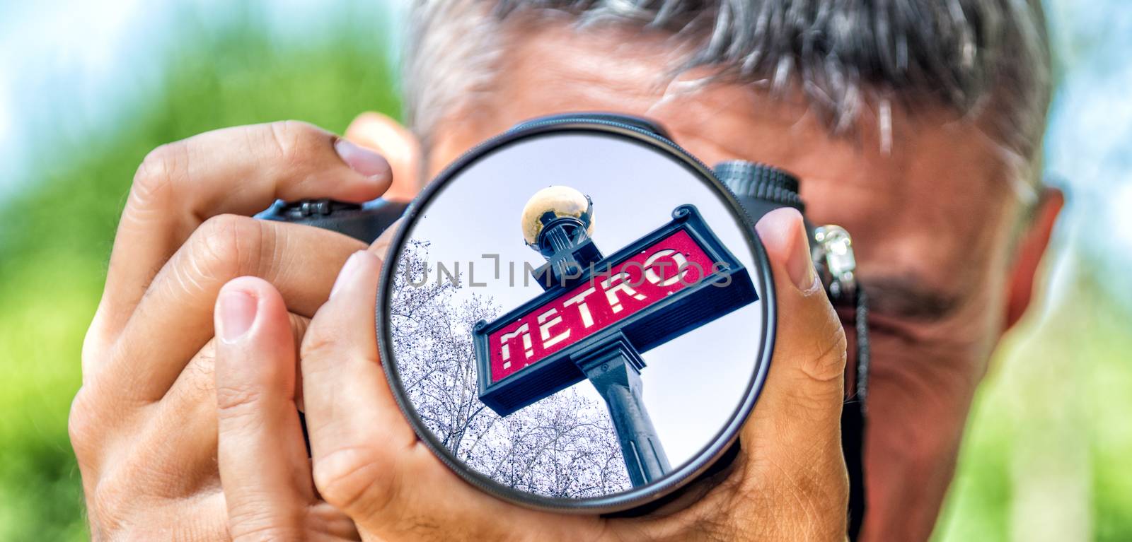 Photographer taking photo with DSLR camera at metro sign in Paris. Shallow DOF