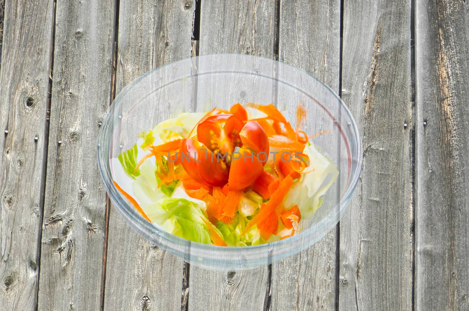 Small glass bowl of salad as background verwittterte wooden boards.
