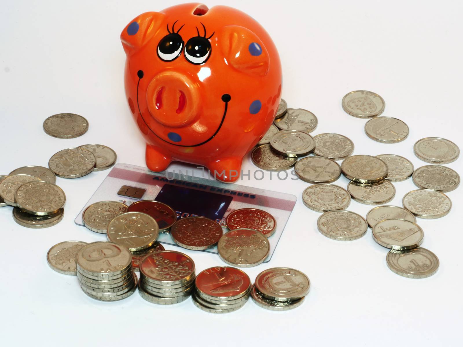 Bunch of Latvian lat coins and piggy bank on white background