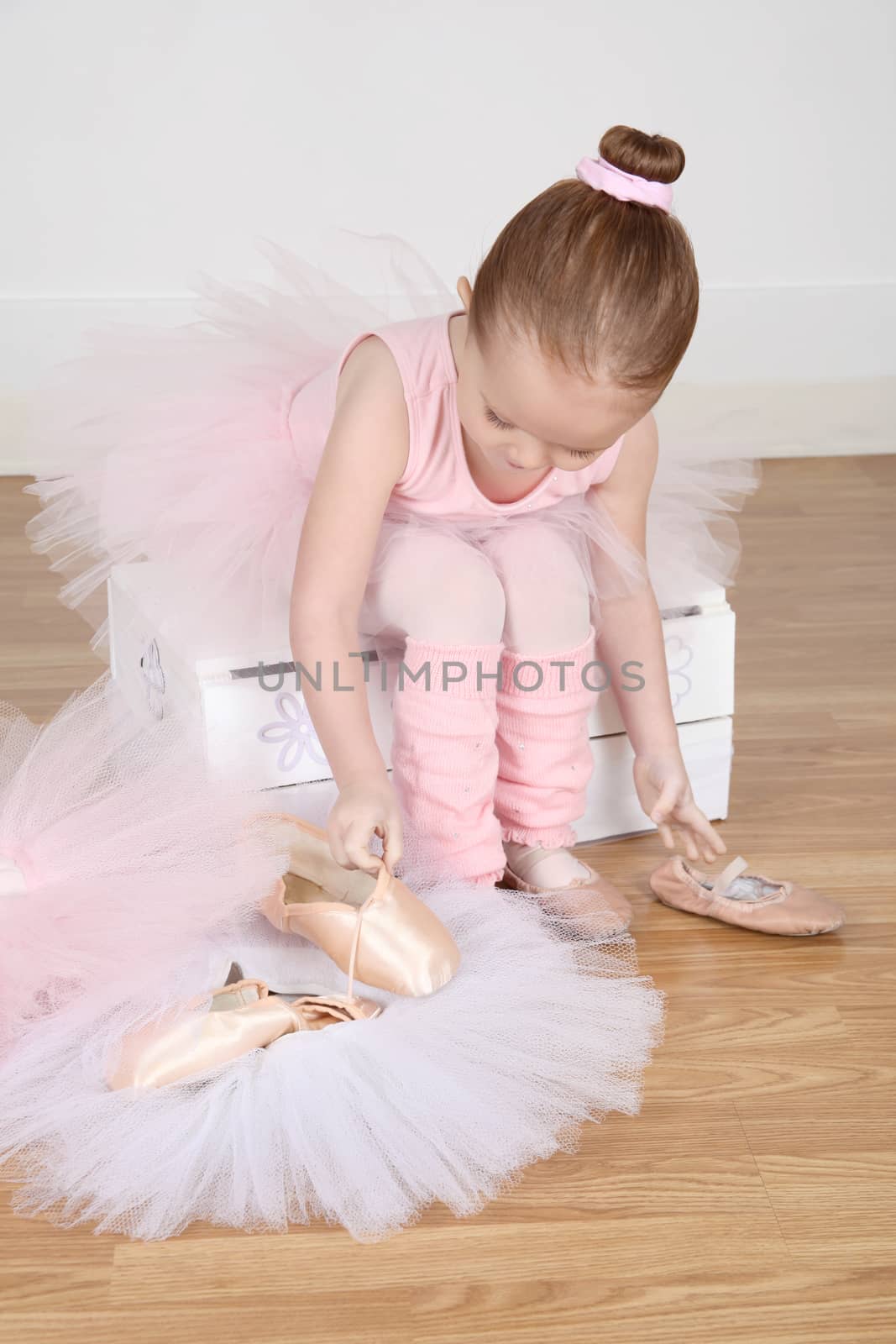 Little ballet girl trying on shoes at the ballet studio